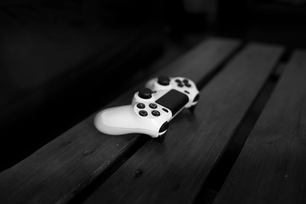 Black and white photo of a gaming controller on a wooden table, perfect for gaming or tech themes.