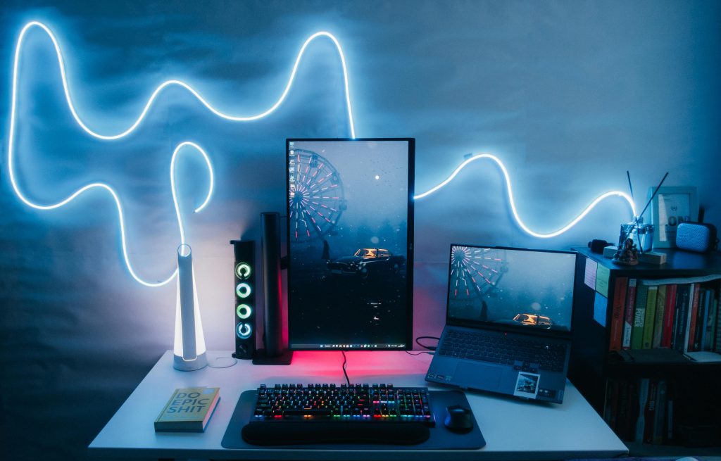 Contemporary desk setup featuring laptops, a vertical monitor, and stylish LED light decoration.