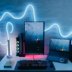 Contemporary desk setup featuring laptops, a vertical monitor, and stylish LED light decoration.