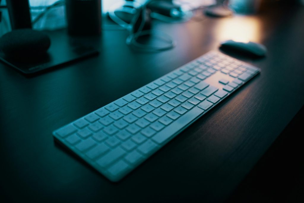 A modern wireless keyboard placed on a sleek desk, illuminated by ambient lighting in a tech-savvy office setting.